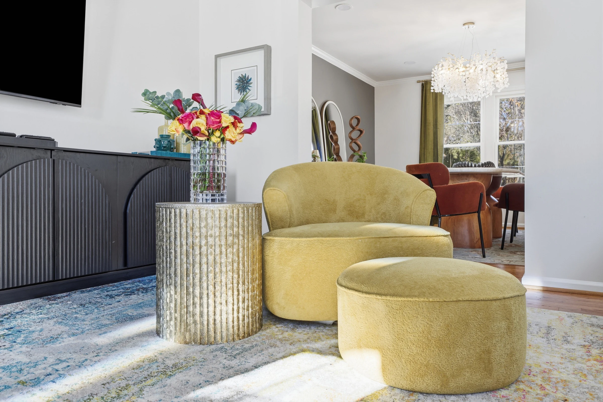 House of Benenate interior design detail with a sculptural mustard chair, black credenza, and colorful accents