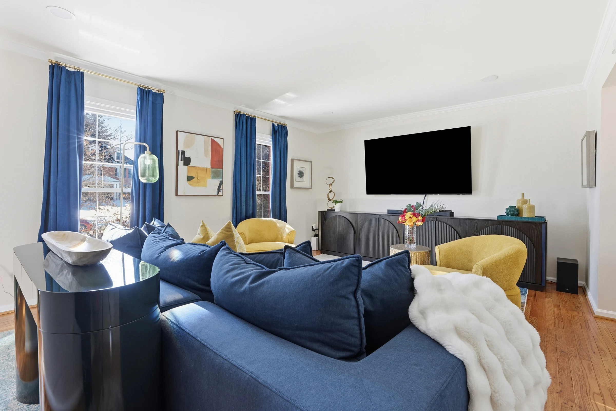 Bright House of Benenate living room with deep blue seating, mustard chairs, and colorful artwork