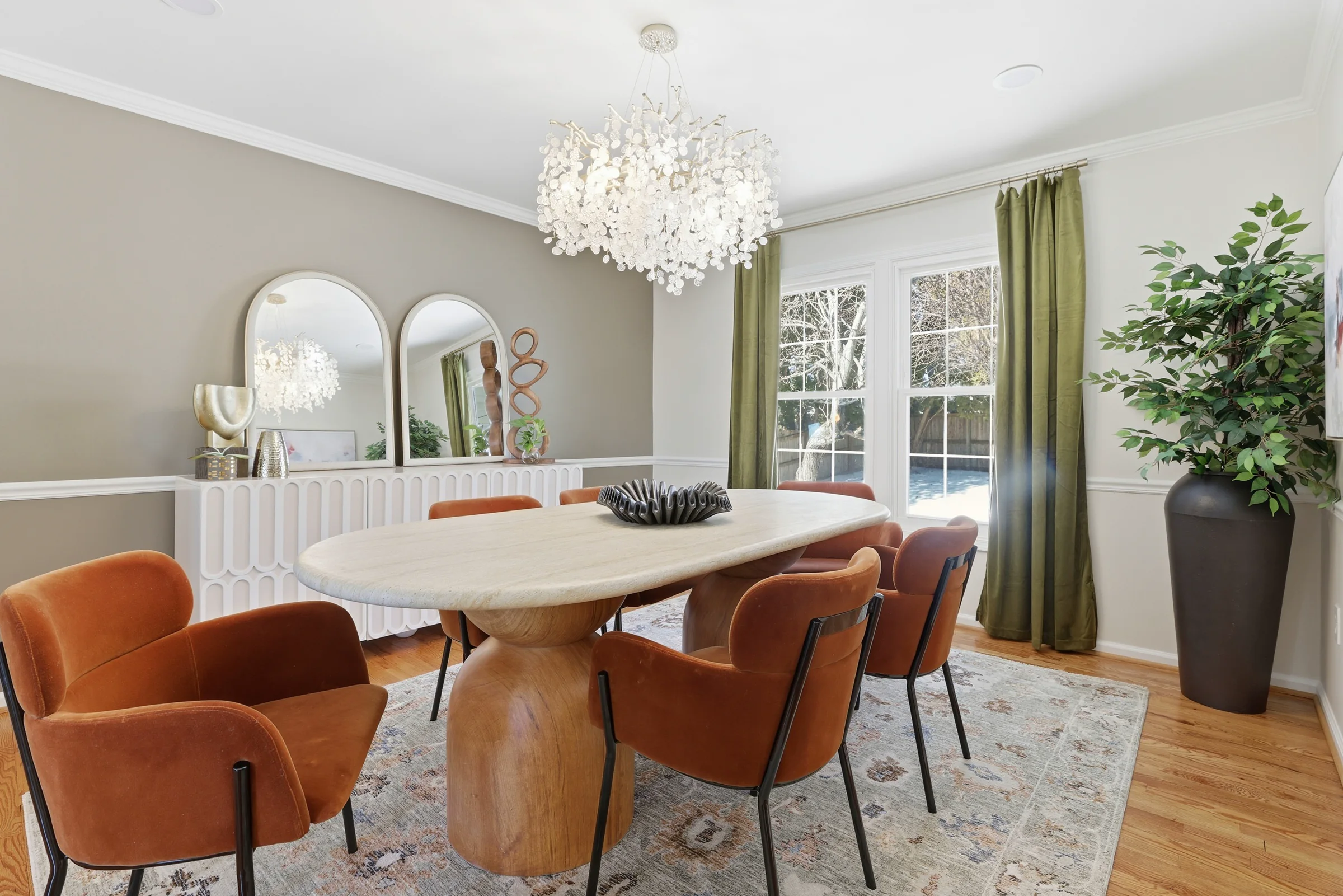 House of Benenate dining room design with rust-colored chairs, sculptural lighting, arched mirrors, and olive drapery