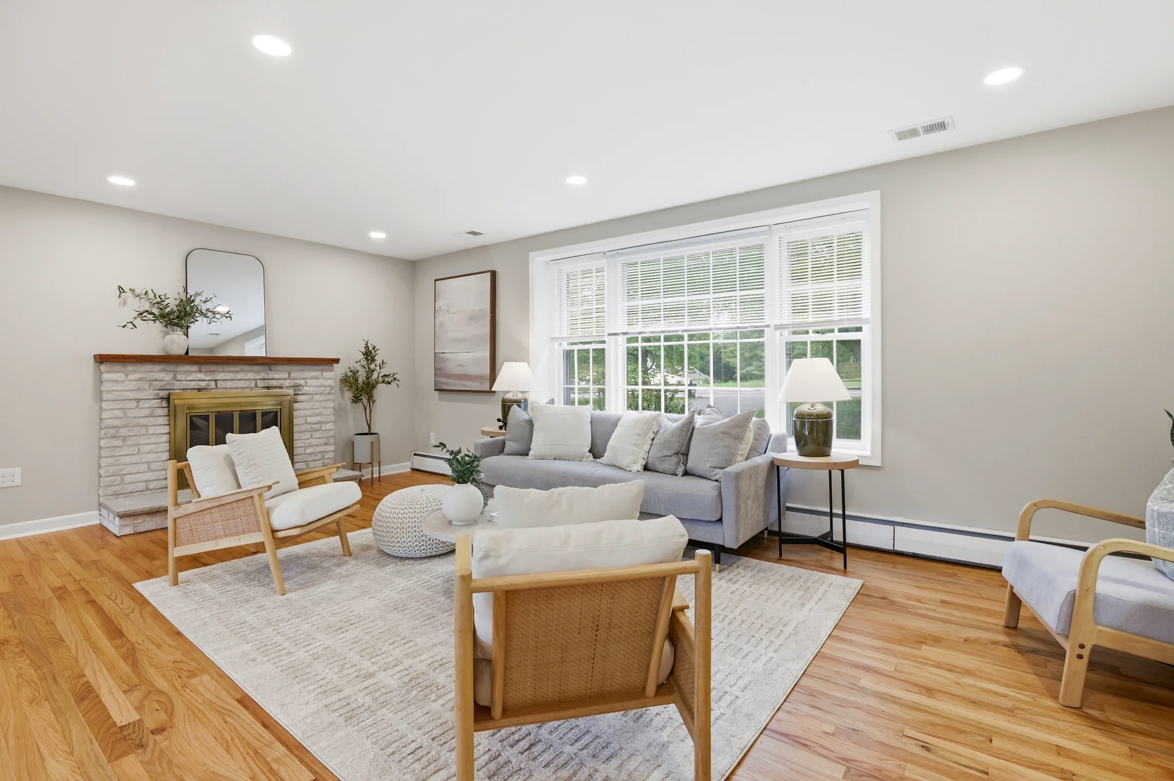Professionally staged 14721 New Hampshire Avenue living room with neutral furnishings, a stone fireplace, and abundant natural light