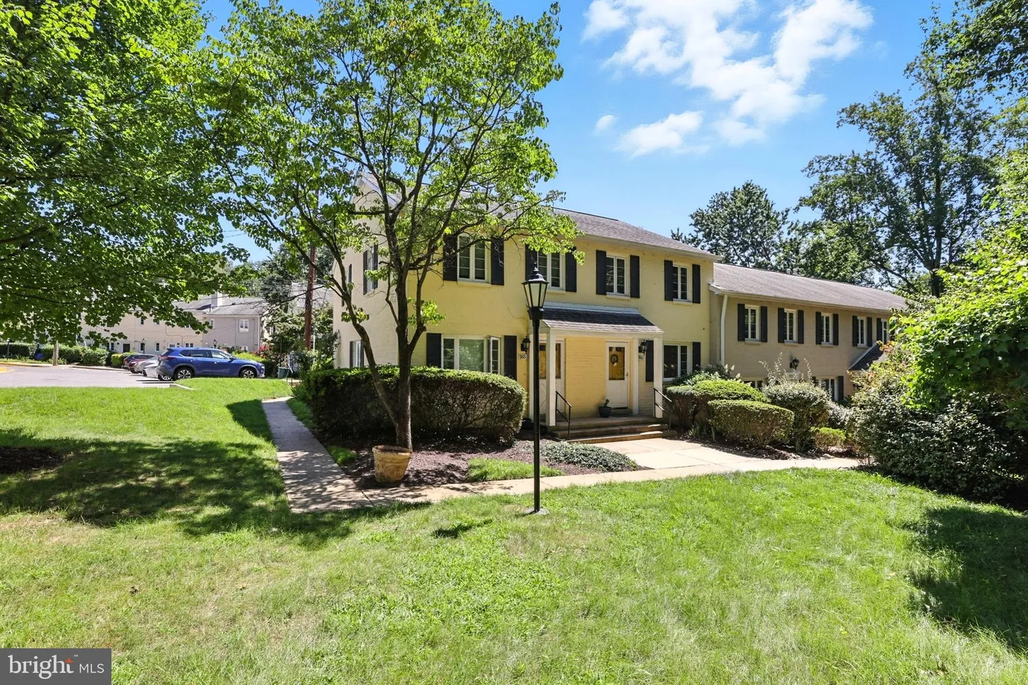 Exterior view of 9882 Hollow Glen Place in Silver Spring with a yellow facade, dark shutters, and lush lawn